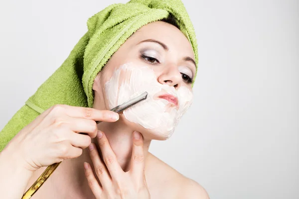 Beautiful Young woman dressed in a bath towel shaves with a straight razor. beauty industry and home skin care concept, extreme Beauty — Stock Photo, Image