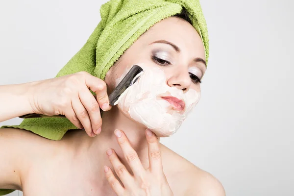 Beautiful Young woman dressed in a bath towel shaves with a straight razor. beauty industry and home skin care concept, extreme Beauty — Stock Photo, Image