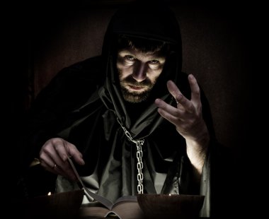 karanlık bir arka plan üzerinde mum ışığında kalın antik kitaptan büyü büyücü çevirir