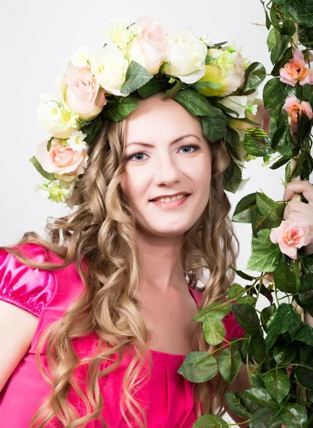 Schöne junge langbeinige Blondine in einem kleinen roten Kleid auf dem Kopf Kranz von Blumen, Seil umwickelt Weinstock und Efeu — Stockfoto