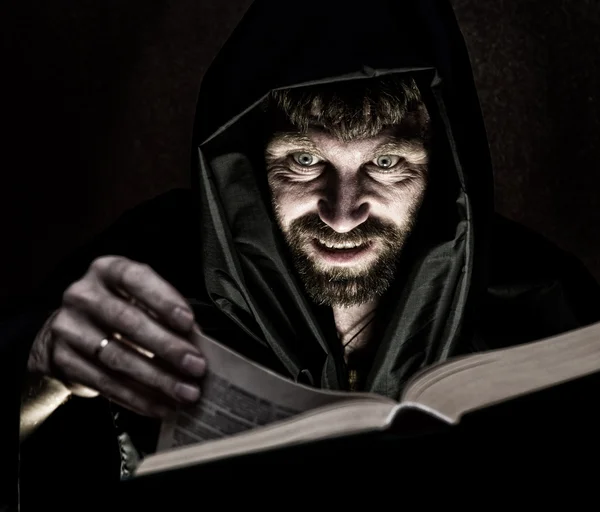 karanlık bir arka plan üzerinde mum ışığında kalın antik kitaptan büyü büyücü çevirir