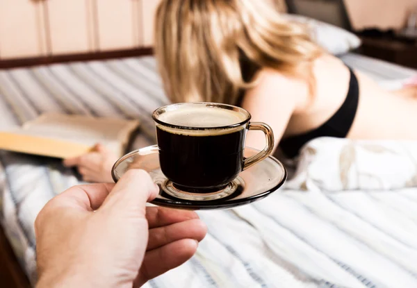 Bela mulher lendo um livro grosso deitado na cama, close-up xícara de café — Fotografia de Stock