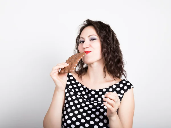 Hermosa mujer joven comiendo una barra de chocolate, lleva un vestido con lunares — Foto de Stock