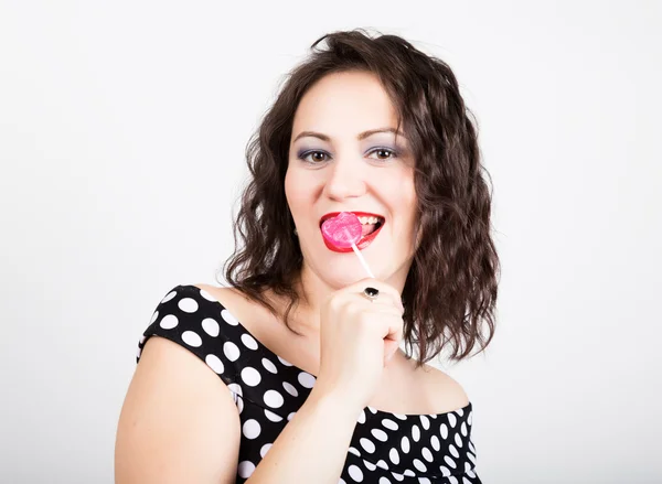 Retrato de feliz hermosa joven lamiendo chupa chups. bonita mujer con corazón en forma de piruleta — Foto de Stock