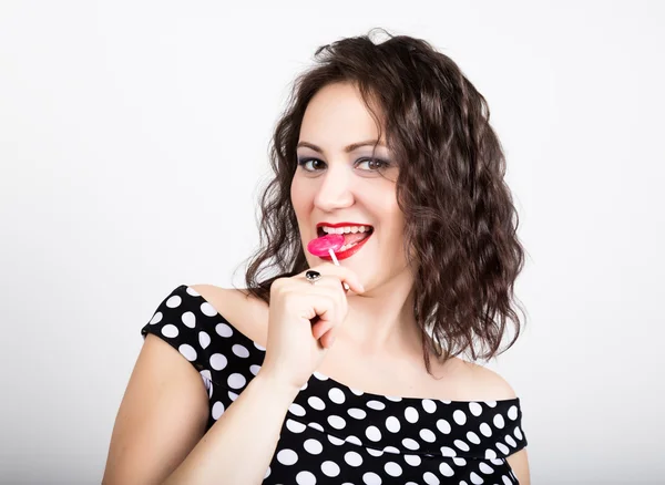 Retrato de feliz hermosa joven lamiendo chupa chups. bonita mujer con corazón en forma de piruleta —  Fotos de Stock