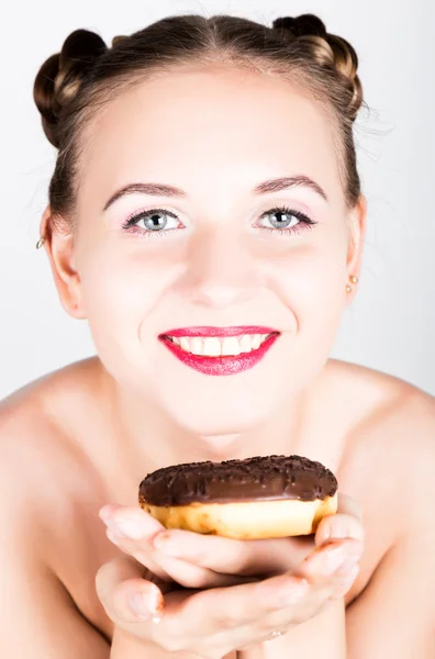 Девушка в ярком макияже ест вкусный пончик с глазурью. Смешная радостная женщина со сладостями, десертом. Концепция диеты. нездоровое питание — стоковое фото