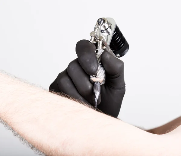 Primer plano de las manos del tatuador en guantes negros con máquina de tatuaje — Foto de Stock