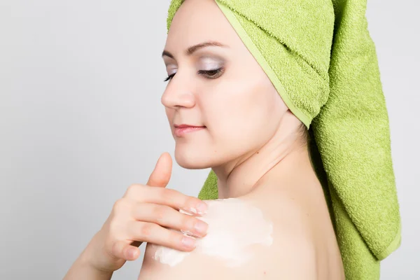 Piękna młoda kobieta ubrana w ręcznik kąpielowy sprawia, że kosmetyk maski na twarzy. piękno przemysł i domu skóry opieki koncepcja — Zdjęcie stockowe