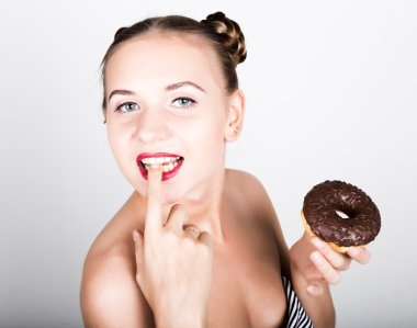 genç kadın olarak parlak makyaj buzlanma ile lezzetli bir poğaça yemek. Komik neşeli kadın tatlılar, tatlı. diyet kavramı. abur cubur. Parmaklarını yalama kız