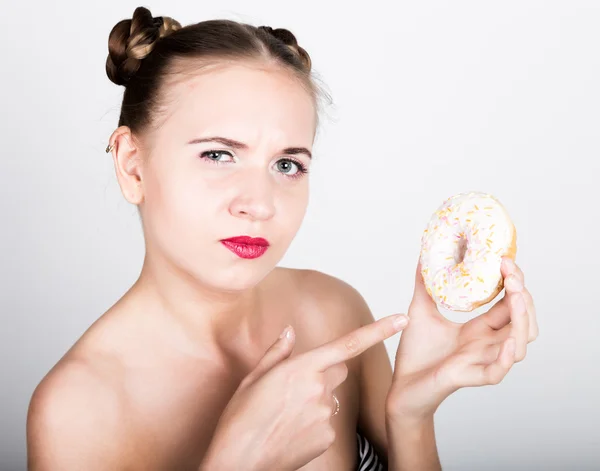 Νεαρή γυναίκα στο λαμπερό μακιγιάζ που τρώει ένα νόστιμο ντόνατ με γλάσο. Αστεία γυναίκα χαρούμενη με γλυκά, επιδόρπιο. δίαιτα έννοια. Πρόχειρο φαγητό. κορίτσι γλείφει τα δάχτυλά τους — Φωτογραφία Αρχείου