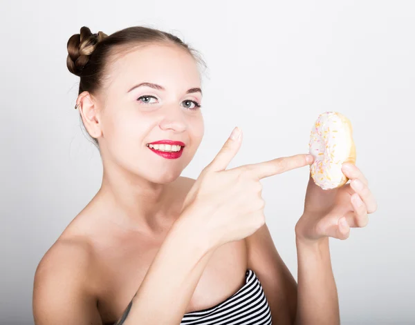 Mujer joven en maquillaje brillante comiendo una rosquilla sabrosa con glaseado. Mujer divertida y alegre con dulces, postre. concepto de dieta. comida chatarra. chica lamiendo sus dedos — Foto de Stock