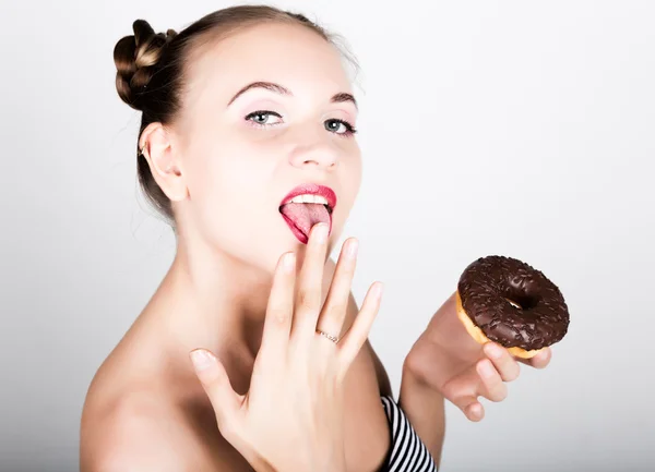 Mujer joven en maquillaje brillante comiendo una rosquilla sabrosa con glaseado. Mujer divertida y alegre con dulces, postre. concepto de dieta. comida chatarra. chica lamiendo sus dedos — Foto de Stock