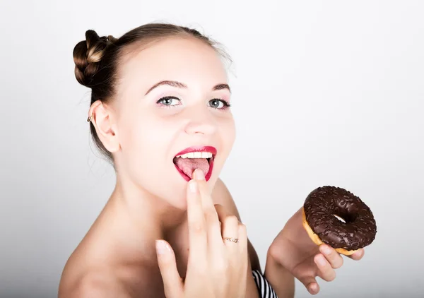 Ung kvinna i ljusa makeup äta en välsmakande donut med glasyr. Funny glad kvinna med godis, dessert. bantning koncept. skräpmat. tjej slickar sina fingrar — Stockfoto