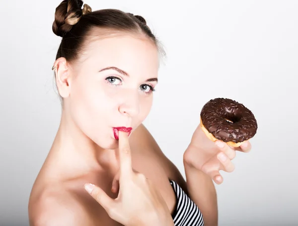 Ung kvinna i ljusa makeup äta en välsmakande donut med glasyr. Funny glad kvinna med godis, dessert. bantning koncept. skräpmat. tjej slickar sina fingrar — Stockfoto