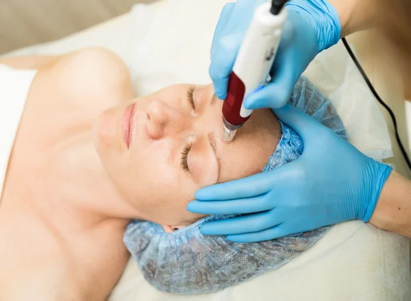 A esteticista faz a mesoterapia fracionada à mulher jovem. Os procedimentos cosméticos para o rosto. Tratamentos de beleza no salão de spa. Cuidados com a pele facial — Fotografia de Stock