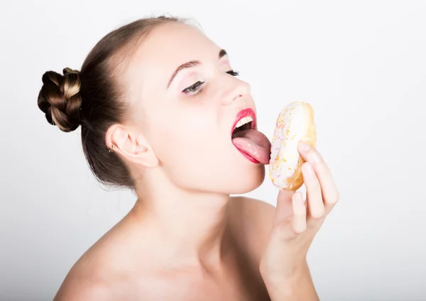 Дівчина в яскравому макіяжі їсть смачний пончик з глазур'ю. Весела радісна жінка з цукерками, десерт. концепція дієти. солодка їжа — стокове фото
