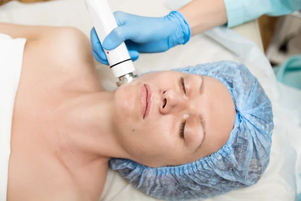 La esteticista hace RF-lifting a la mujer joven. Los procedimientos cosméticos para la cara. Tratamientos de belleza en el salón de spa. Cuidado facial de la piel —  Fotos de Stock