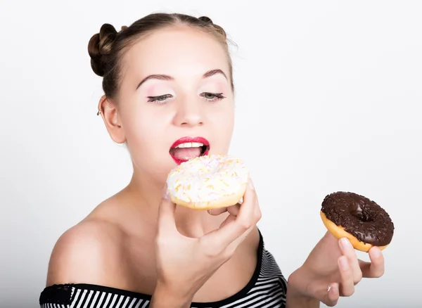 Девушка в ярком макияже ест вкусный пончик с глазурью. Смешная радостная женщина со сладостями, десертом. Концепция диеты. нездоровое питание — стоковое фото