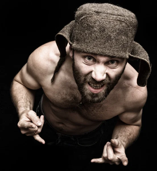怖い邪悪な不吉なひげの男の暗い肖像画は、様々な手の兆候を作り、異なる感情を表現します。裸の胴とウールの帽子を持つ奇妙なロシアの男 — ストック写真