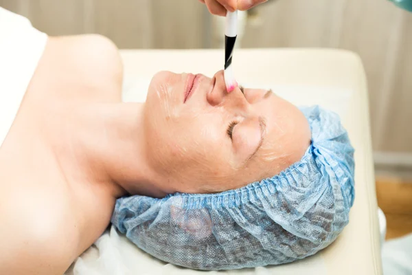 Giovane donna sdraiata in un salone termale e con un trattamento di bellezza del viso. Le procedure cosmetiche per il viso. Trattamenti estetici nel salone termale. Cura della pelle facciale — Foto Stock