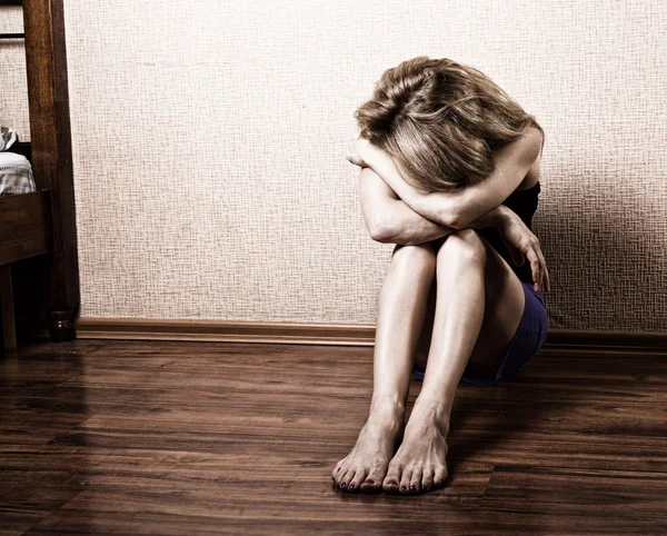 Triste mujer sentada sola en una habitación vacía junto a la cama. violencia doméstica —  Fotos de Stock