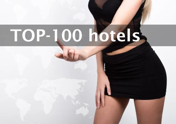 Top 100 hoteles escritos en una pantalla virtual. Tecnologías de Internet en negocios y turismo. mujer en pequeño dres negro, presiona un dedo en una pantalla virtual — Foto de Stock