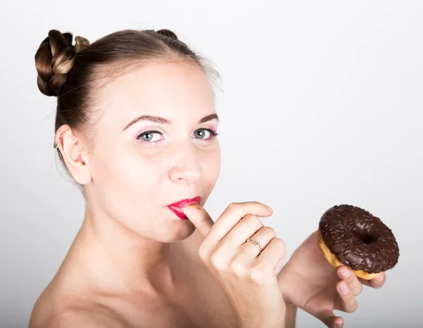 Дівчина в яскравому макіяжі їсть смачний пончик з глазур'ю. Весела радісна жінка солодощі, десерт. концепція дієти. солодка їжа. облизуючи пальцями — стокове фото
