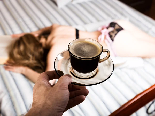 Belle femme lisant un livre épais couché sur le lit, tasse de café gros plan — Photo