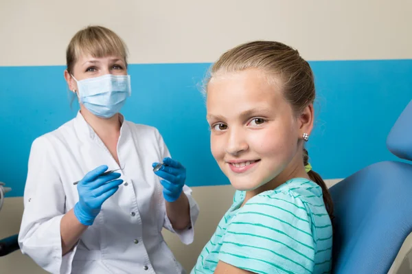 Menina feliz com a boca aberta em tratamento dentário na clínica. Dentista verificado e curar os dentes de uma criança paciente no consultório odontológico — Fotografia de Stock