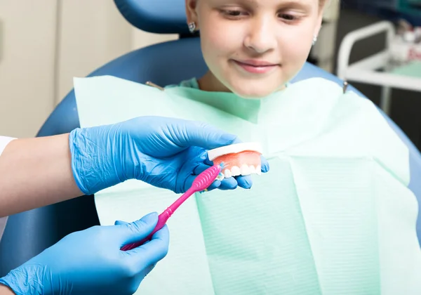 Gelukkig klein meisje met open mond tandheelkundige behandeling bij kliniek ondergaat. tandarts een kind laat zien hoe goed hun tanden te poetsen — Stockfoto