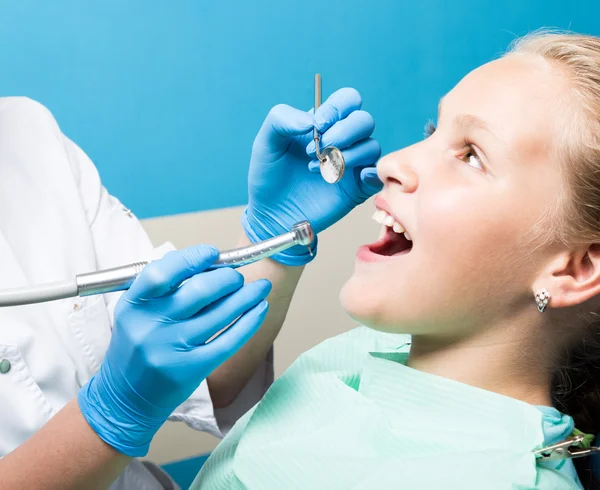 Niña feliz con la boca abierta sometida a tratamiento dental en la clínica. El dentista revisó y curó los dientes de un niño paciente en el consultorio dental — Foto de Stock