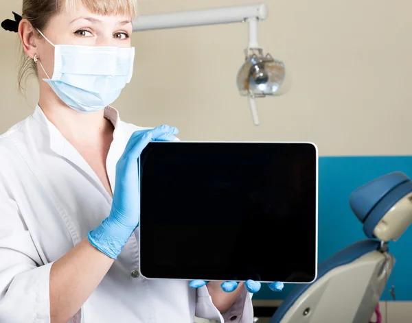 Τεχνολογία, το διαδίκτυο και τη δικτύωση στην ιατρική concept-Femail οδοντίατρου κρατώντας ένα Tablet PC με μια κενή σκοτεινή οθόνη. στο φόντο του οδοντιατρικού εξοπλισμού — Φωτογραφία Αρχείου