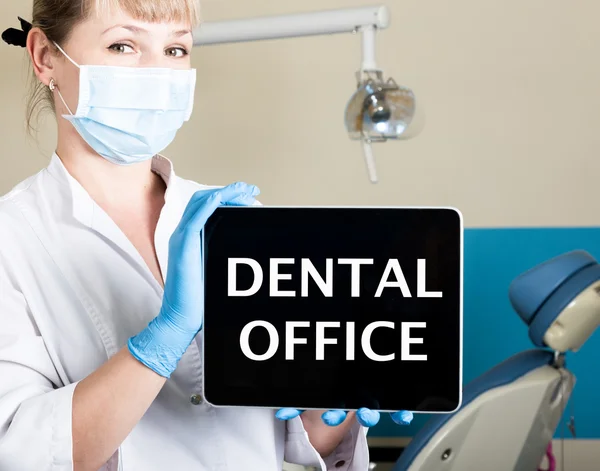 Технологія, Інтернет та мережа в концепції медицини - стоматолог, що тримає планшетний ПК зі знаком стоматологічного кабінету. на фоні стоматологічного обладнання — стокове фото
