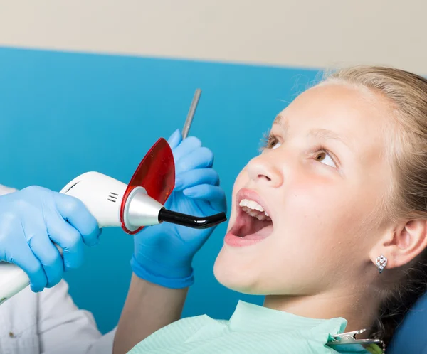 Niña feliz con la boca abierta sometida a tratamiento dental en la clínica. El dentista revisó y curó los dientes de un niño paciente en el consultorio dental — Foto de Stock