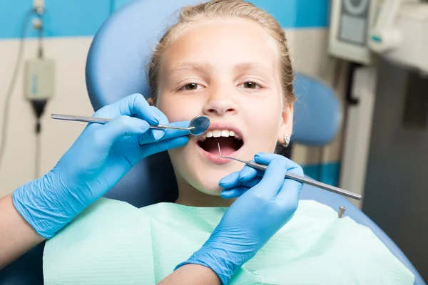 Lycklig liten flicka med öppen mun genomgå tandvård på kliniken. Tandläkaren kollade och bota tänder en barn patient i tandläkarens — Stockfoto