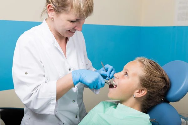 Niña feliz con la boca abierta sometida a tratamiento dental en la clínica. El dentista revisó y curó los dientes de un niño paciente en el consultorio dental — Foto de Stock