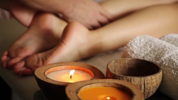 Jeune femme se fait masser les pieds dans le salon de spa. gros plan des bougies. mains masculines glissent sur les jambes féminines — Video