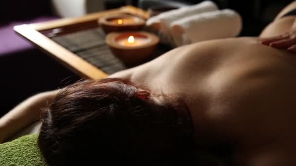 Jovem mulher recebendo uma massagem nas costas no salão de spa. mãos fechadas do massagista — Vídeo de Stock