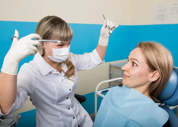 El médico examina la cavidad oral en la caries dental. Protección contra caries. Tratamiento de caries dental. Dentista trabajando con lámpara de polimerización dental en cavidad oral — Foto de Stock