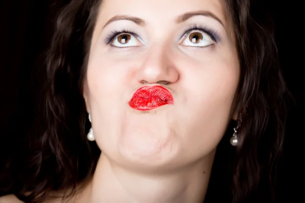 Mulher de close-up olha diretamente para a câmera em um fundo preto. expressa emoções diferentes, enviando um beijo — Fotografia de Stock