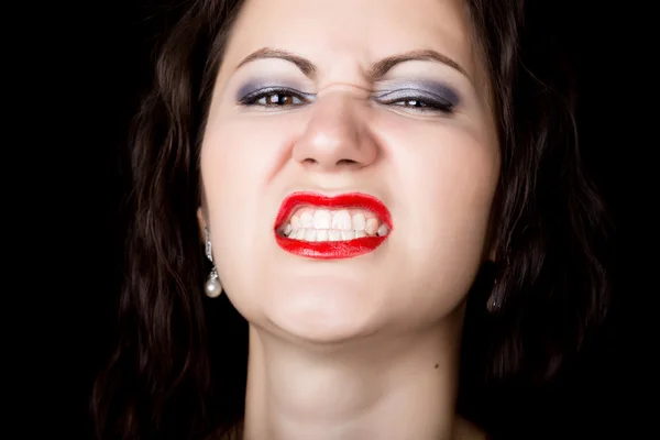 La mujer de cerca mira directamente a la cámara sobre un fondo negro. expresa diferentes emociones, mostrando dientes, mostrando gruñidos de sonrisa — Foto de Stock