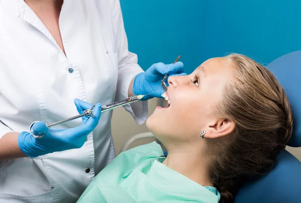 Glückliches kleines Mädchen mit offenem Mund, das sich einer Zahnbehandlung in der Klinik unterzieht. Zahnarzt überprüft und heilt Zähne eines Kinderpatienten in der Zahnarztpraxis — Stockfoto