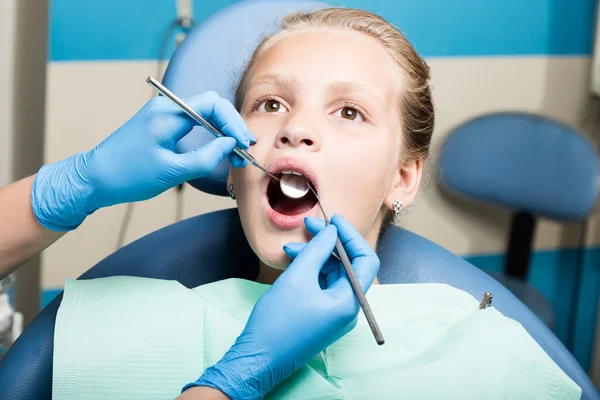 Menina feliz com a boca aberta em tratamento dentário na clínica. Dentista verificado e curar os dentes de uma criança paciente no consultório odontológico — Fotografia de Stock