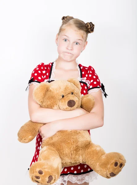 年轻漂亮的女孩穿着一件红色的衣服与白色波尔卡圆点抱着一只泰迪熊 — 图库照片