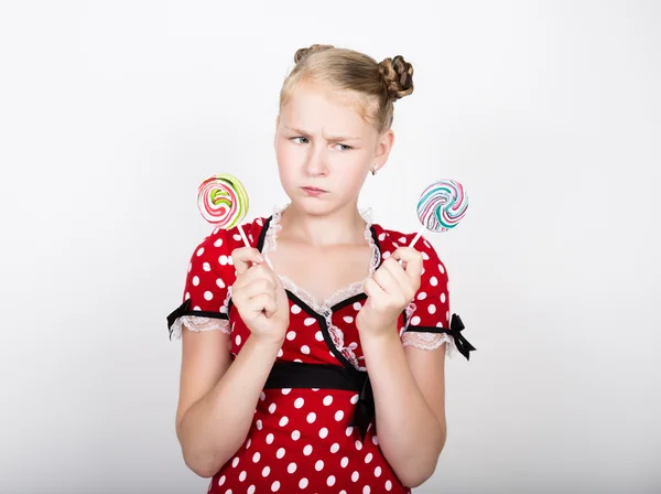 Retrato de menina bonita feliz com doces doces. bonita jovem mulher vestida em um vestido vermelho com bolinhas brancas segurando dois pirulito colorido — Fotografia de Stock