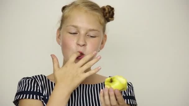Krásná mladá dívka oblečená v pruhovaných šatech jíst jablko. zdravé potraviny - silné zuby koncept — Stock video