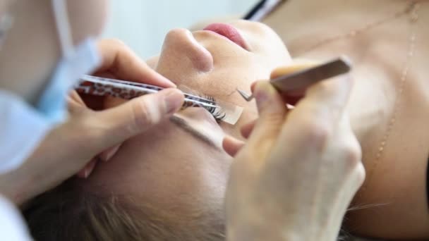 Schöne junge Frau mit Wimpernverlängerung. Frauenauge mit langen Wimpern. Kosmetikerin Wimpernverlängerung für junge Frau im Schönheitssalon — Stockvideo