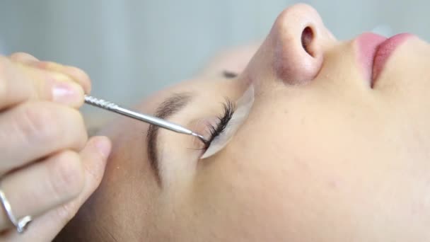 Belle jeune femme avec extension de cils. Œil de femme avec de longs cils. Extension de cils esthéticienne pour jeune femme dans un salon de beauté — Video