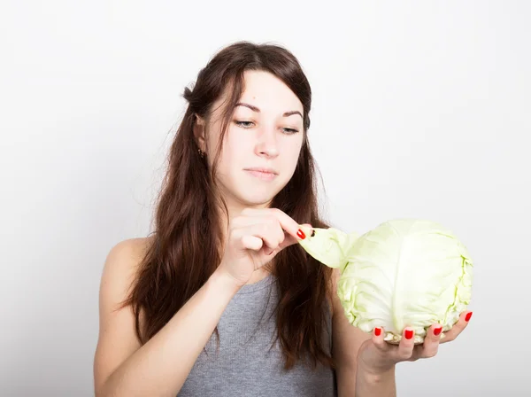 美しい若い女性が、野菜を食べること。彼女を見つめるキャベツを保持、キャベツの頭。健康食品 - 健康なボディのコンセプト — ストック写真