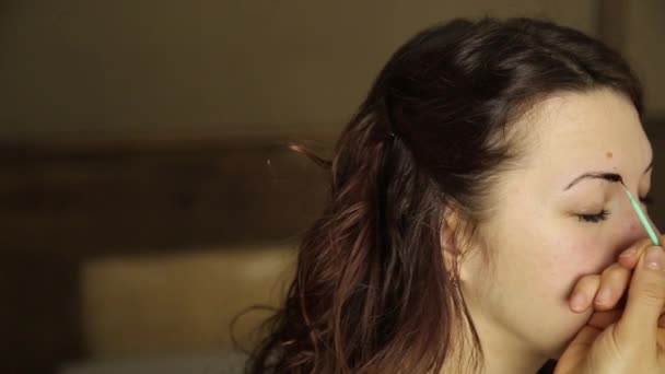 Artista de maquillaje pinta las cejas de una hermosa modelo de chica usando cepillo — Vídeo de stock